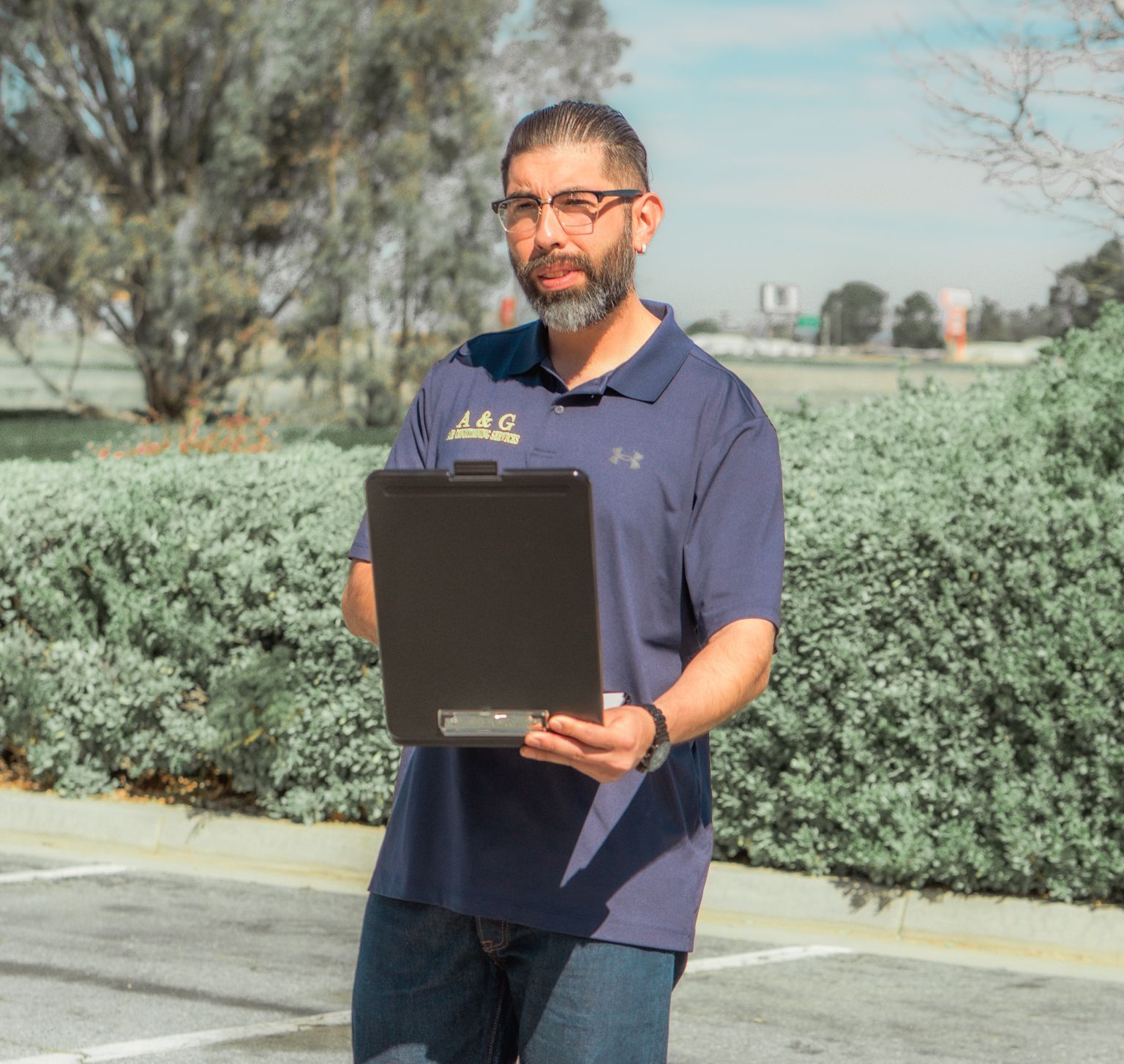 An A & G Technician  in a blue shirt is holding a clipboard in San Bernardino County.