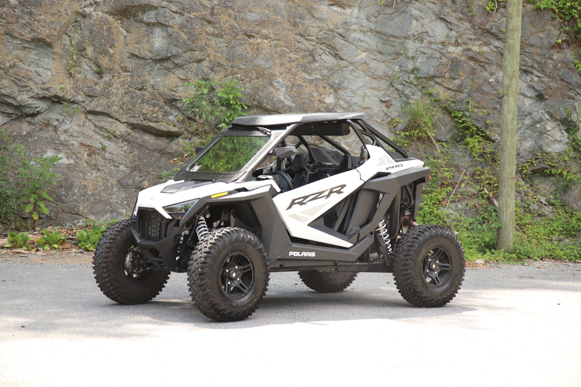 A blue atv is parked on the side of the road in front of a rock wall.