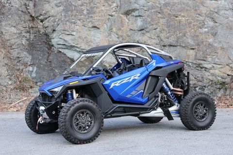 A blue atv is parked on the side of the road in front of a rock wall.