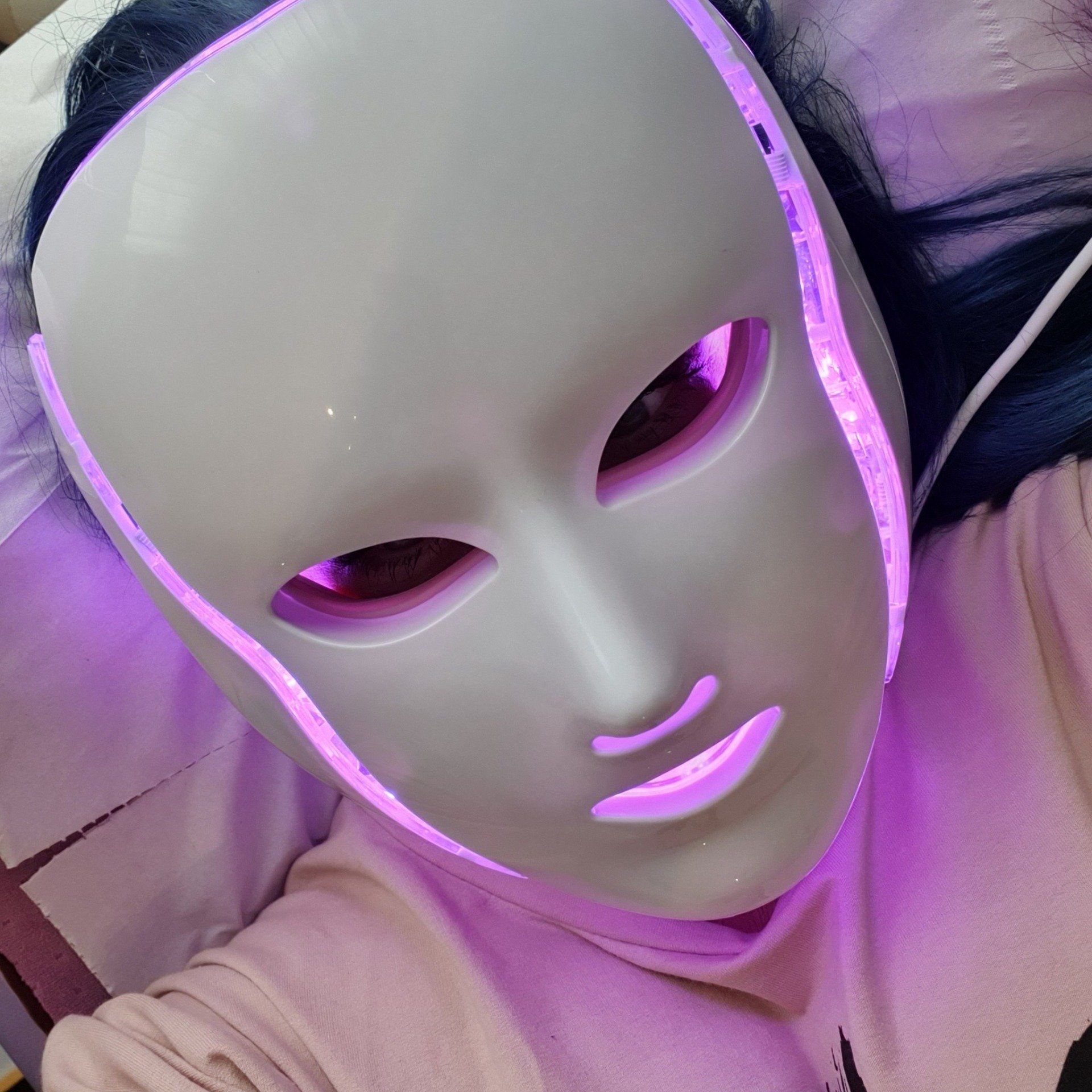 A woman is wearing a white mask with purple lights on it.