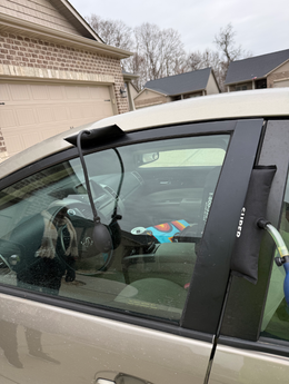A car with a water hose and a black tube inserted in its window; the hose runs from outside to the car's interior.