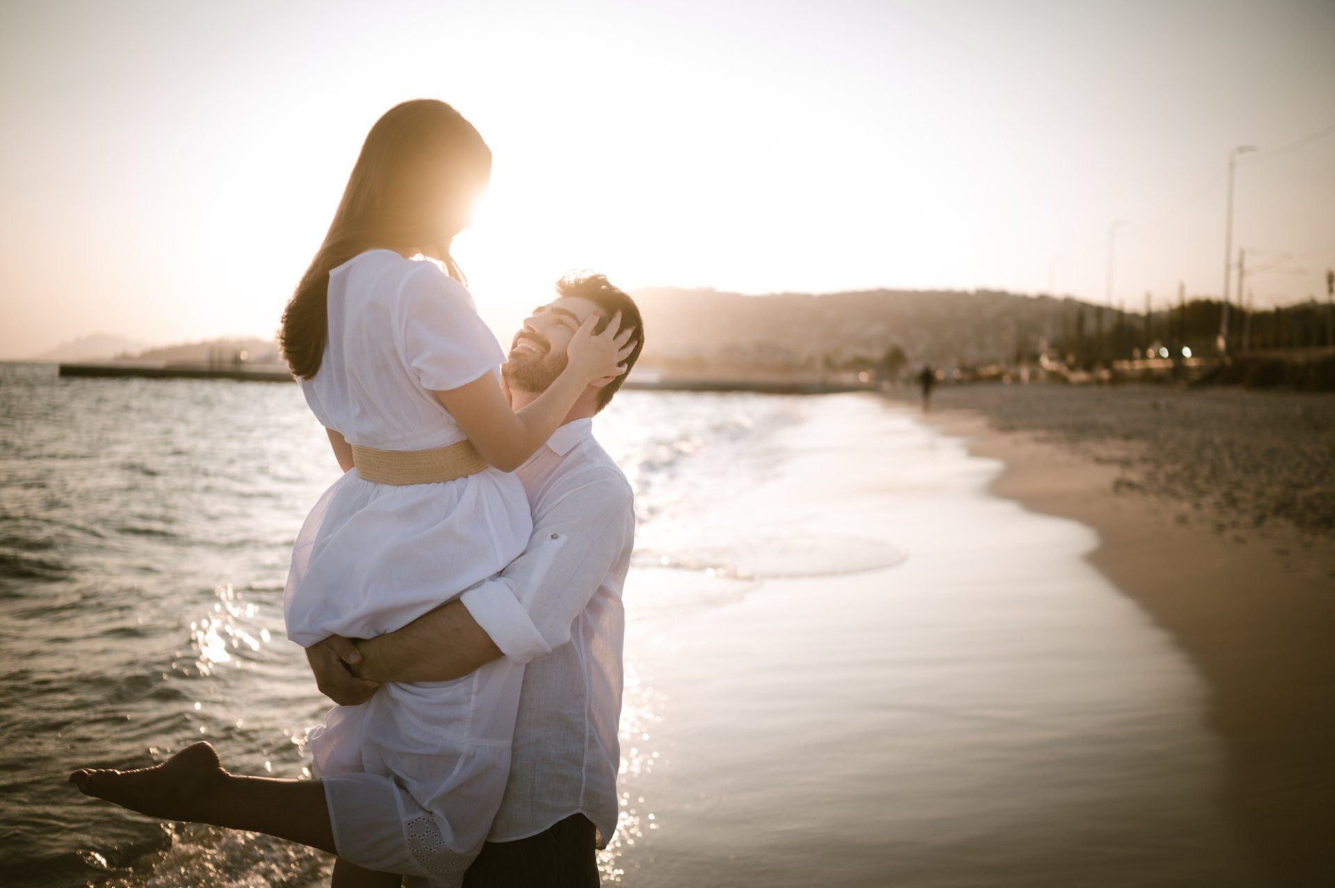 A couple run along a beach at sunset in Antibes