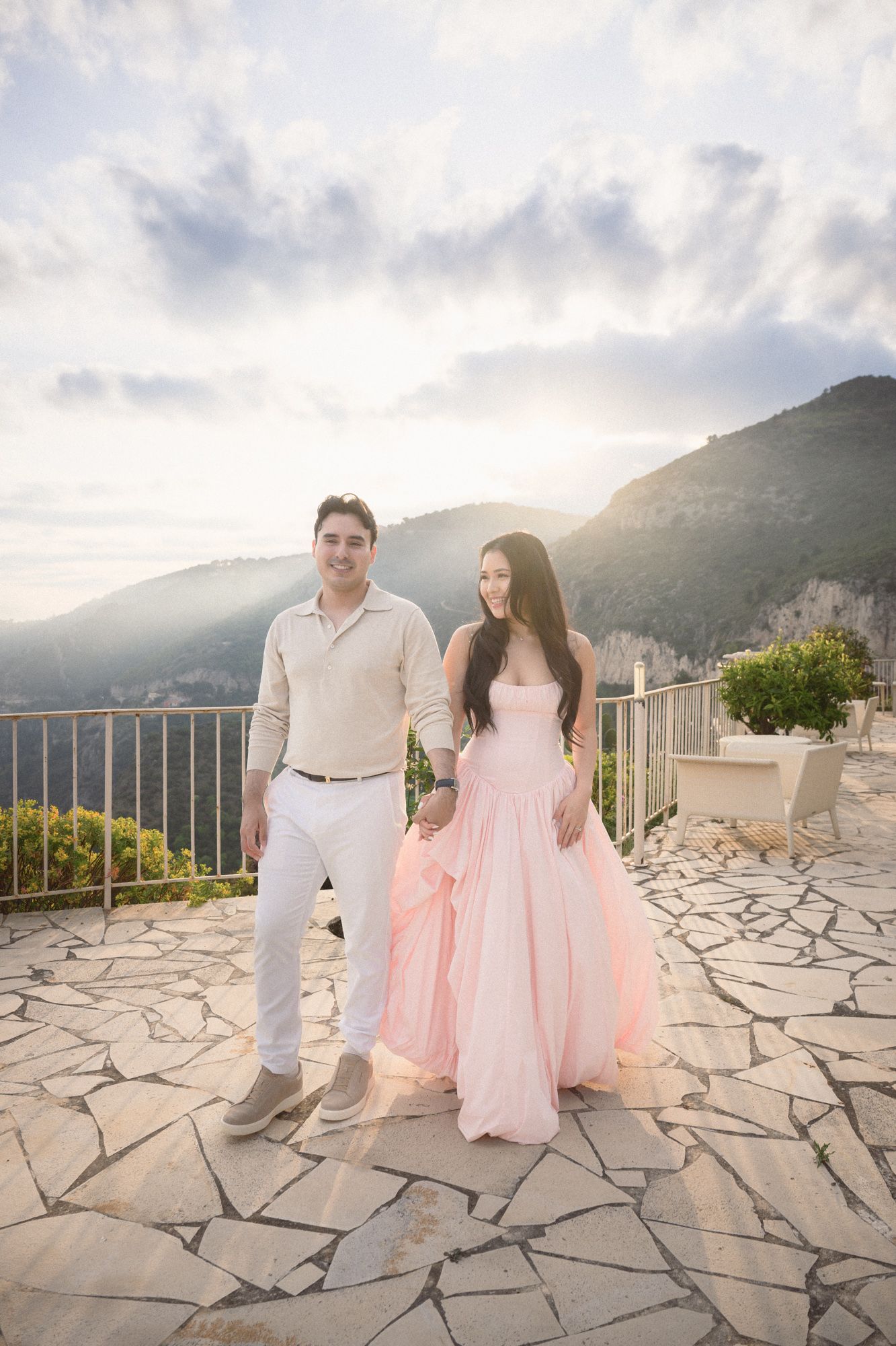 A couple laugh and smile in a candid photo backlit at golden hour on the French Riviera.