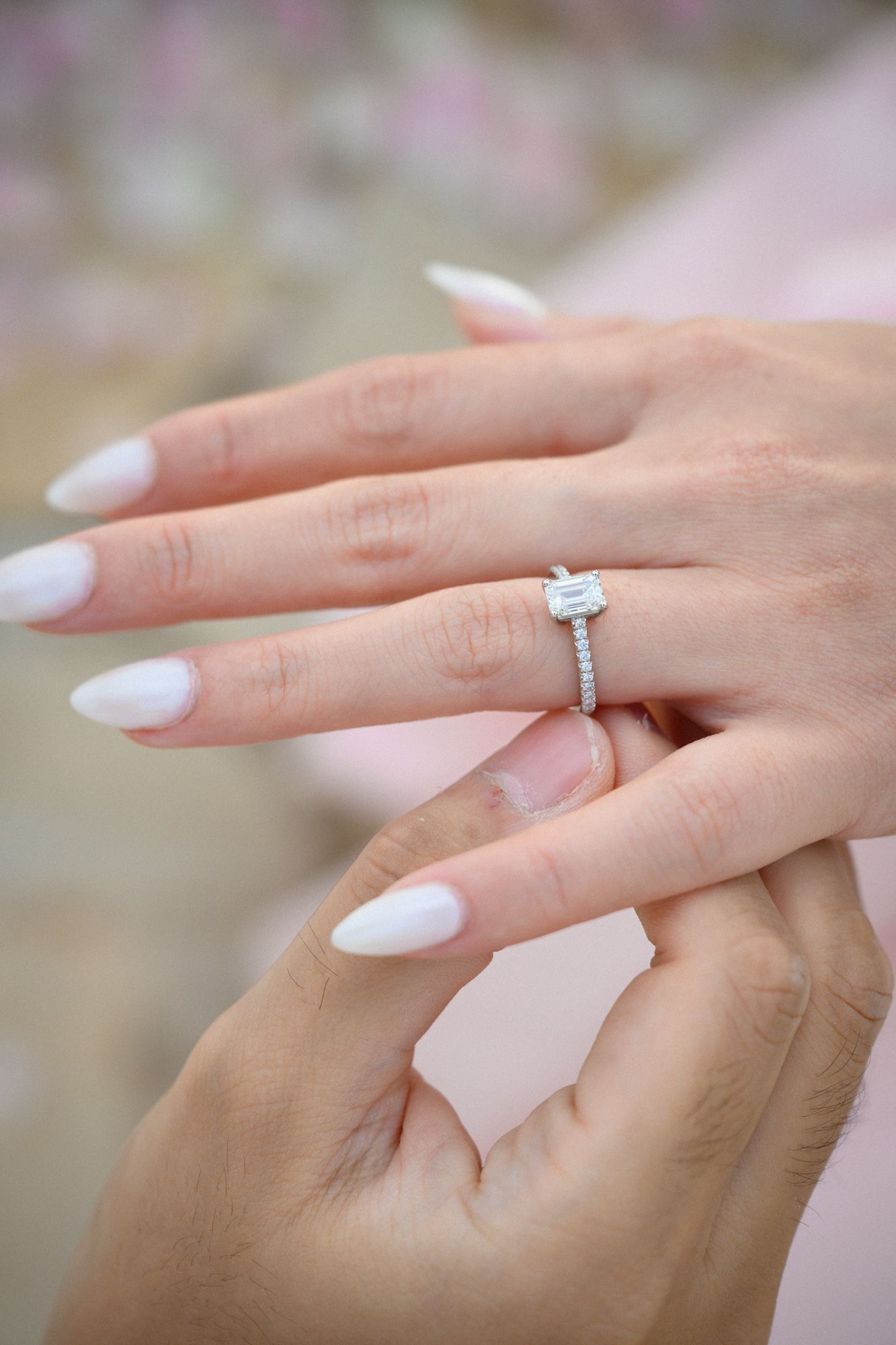 A wedding ring is placed on the bride-to-be's hand during a proposal photoshoot.