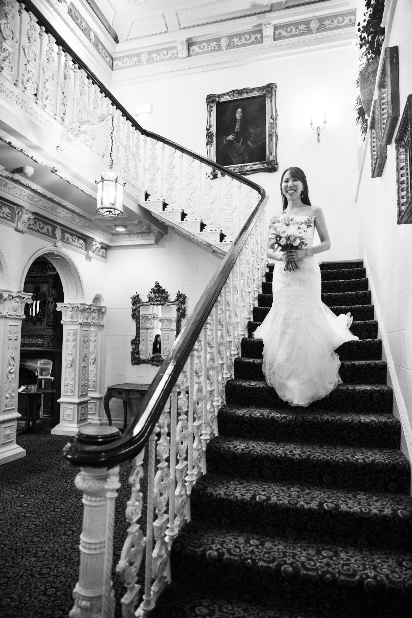 The bride descending the sweeping staircase at Ettington Park wedding venue before her ceremony.