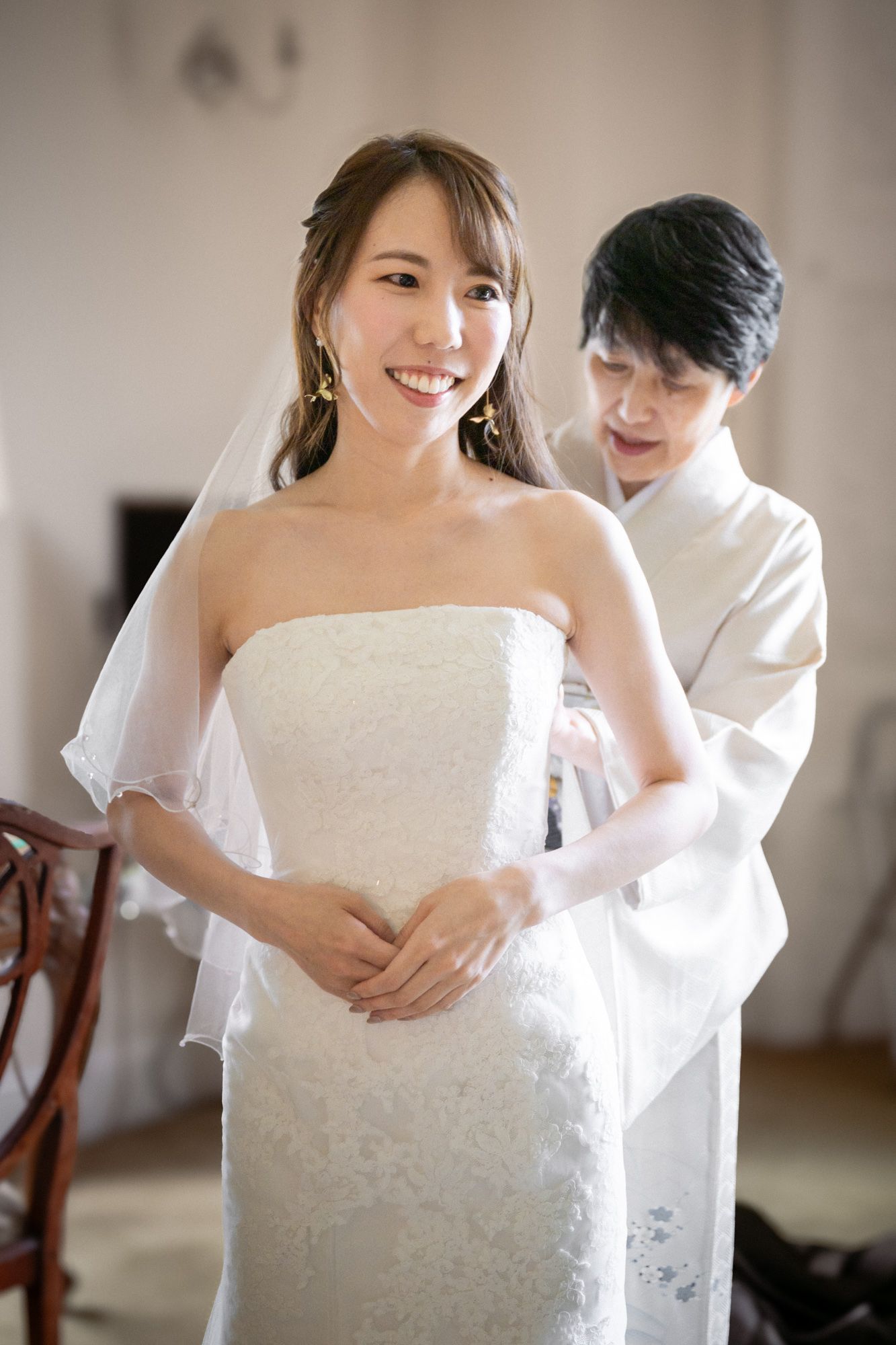 A bride's wedding dress is adjusted by her mother before her wedding ceremony.