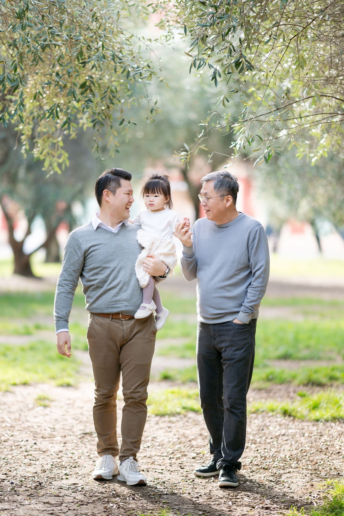 a candid family photo of three generations walking through the park