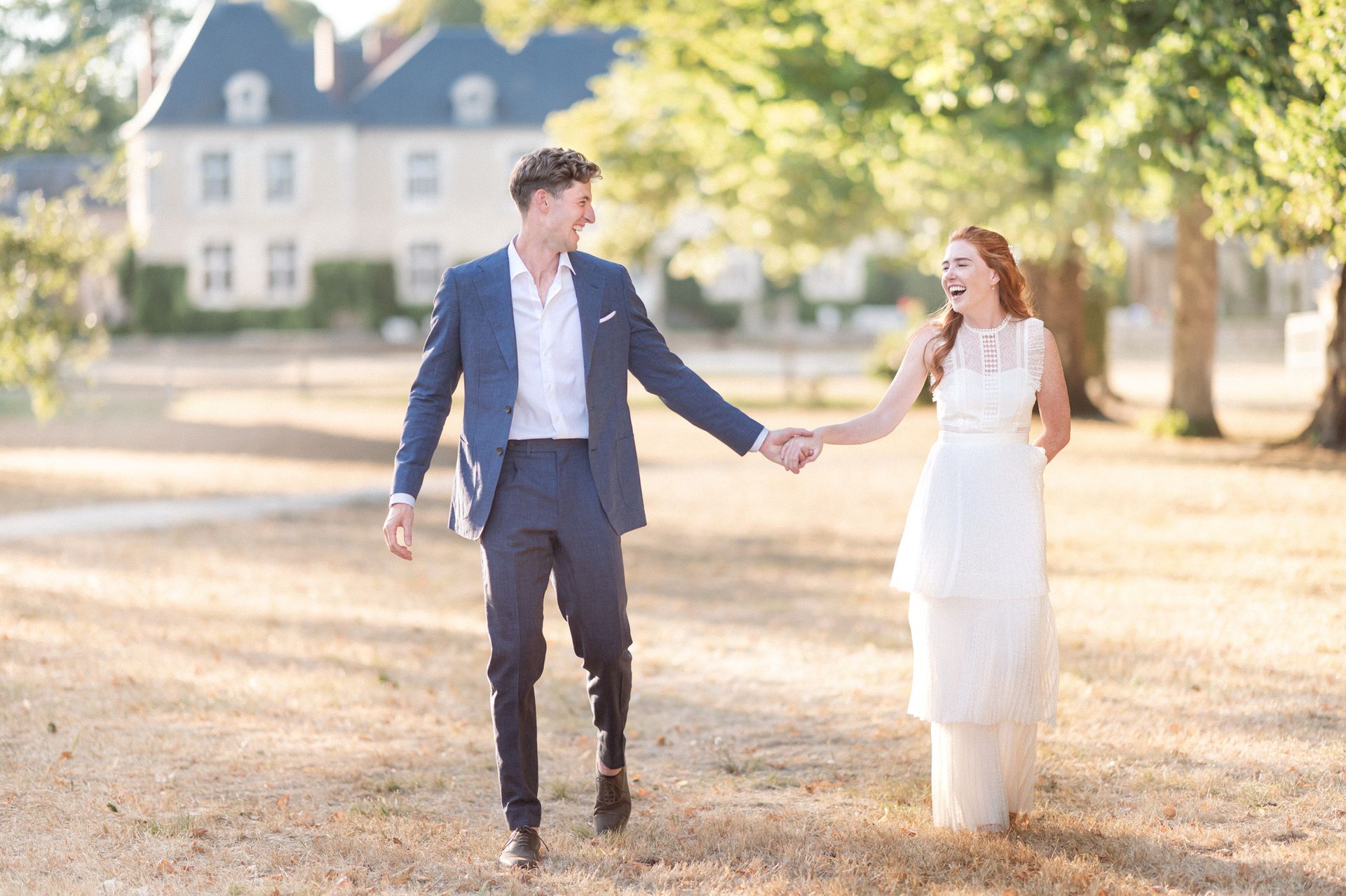 Un couple rit et sourit pendant une séance de photos non posées lors de leur mariage dans un château français.