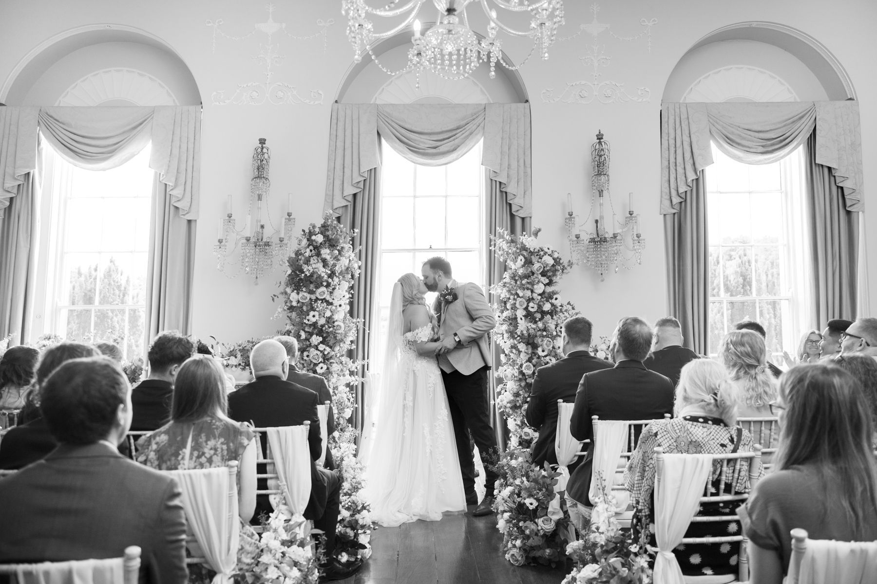 The couple's first kiss at an indoor wedding at Kelmarsh Hall