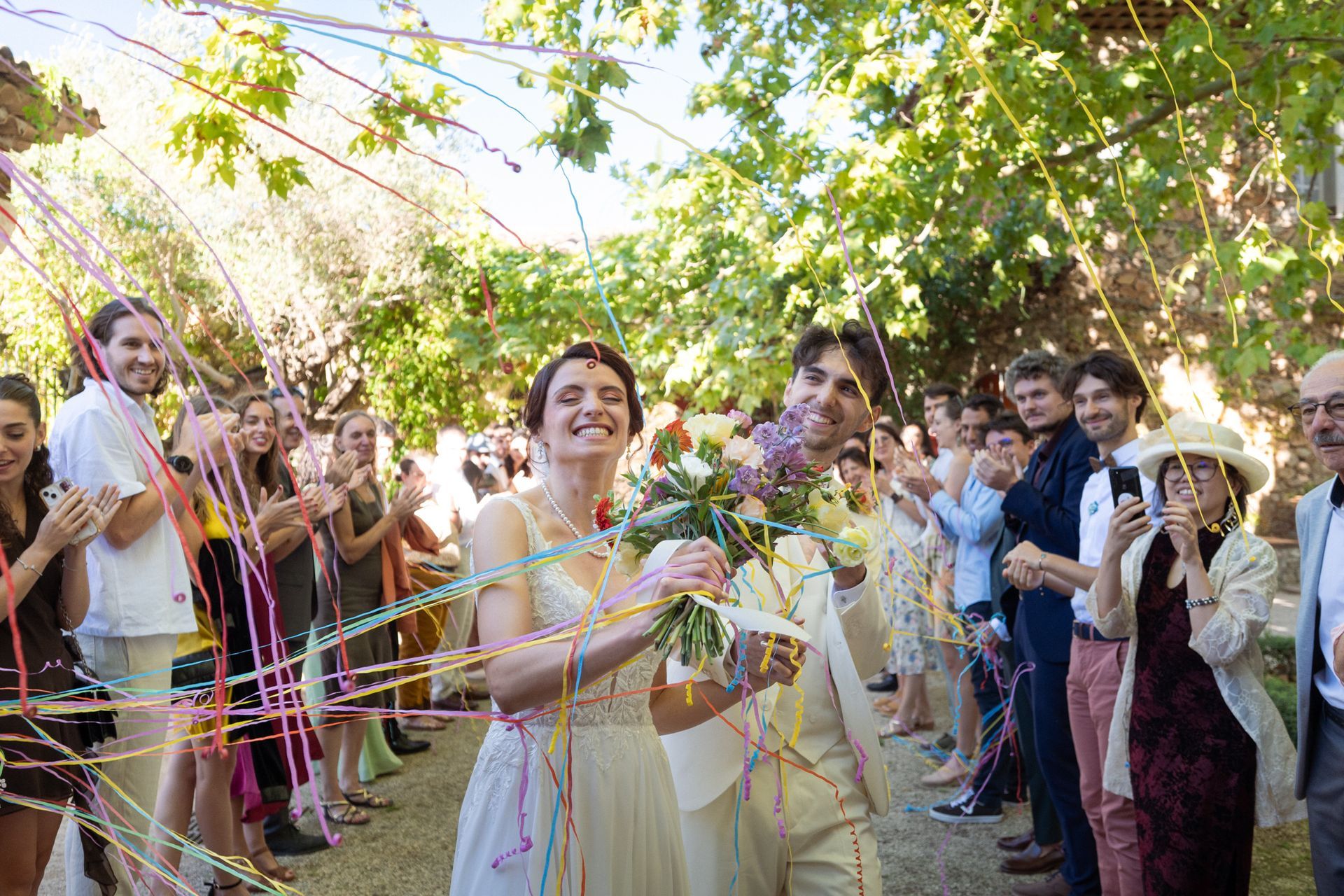 Le couple traverse des banderoles colorées au lieu de confettis au Château Font du Broc.