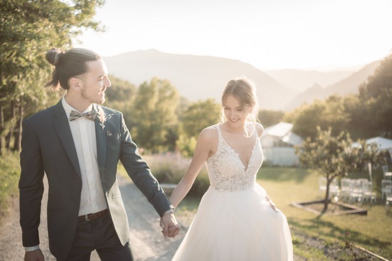 A newly-wed couple walk and smile during a romantic sunset photoshoot 