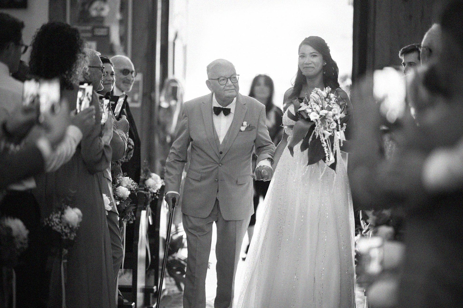 La mariée et son père remontent l'allée centrale.
