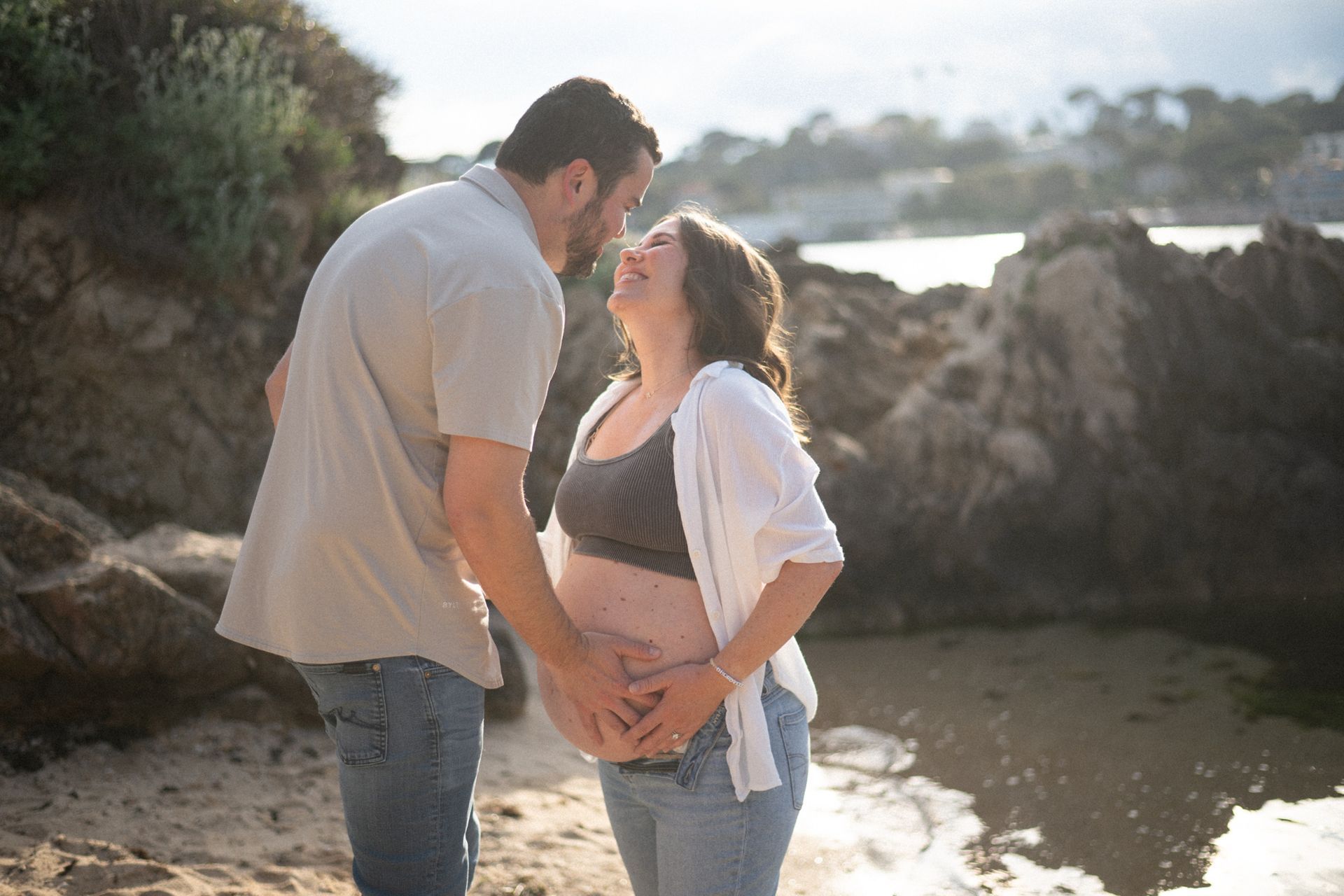 A couple laugh and smile during a maternity photoshoot on the French Riviera