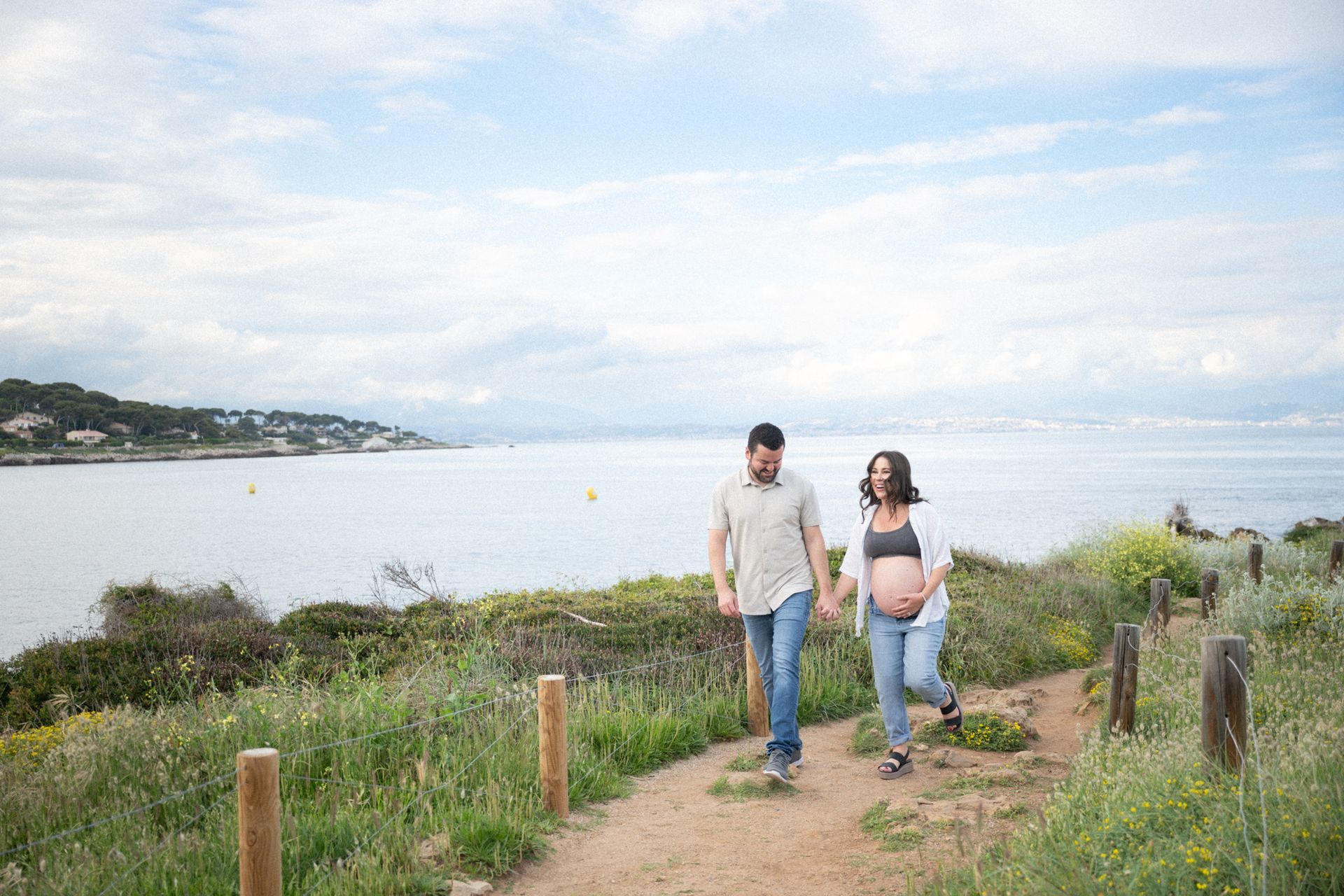 A professional photograph of a pregnant lady walking with her partner during a maternity photoshoot.