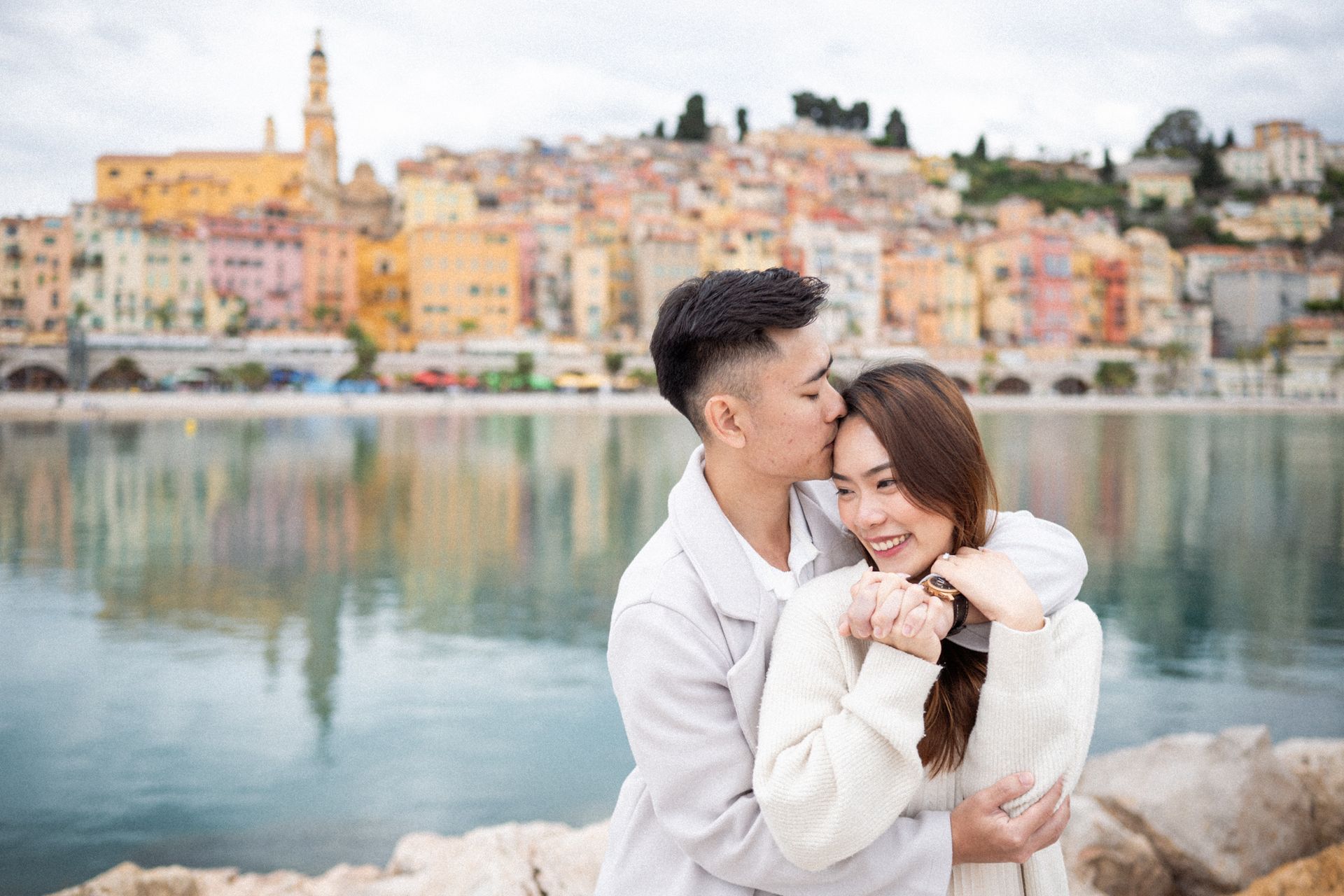 A men kisses his fiancé on the rocks in Menton