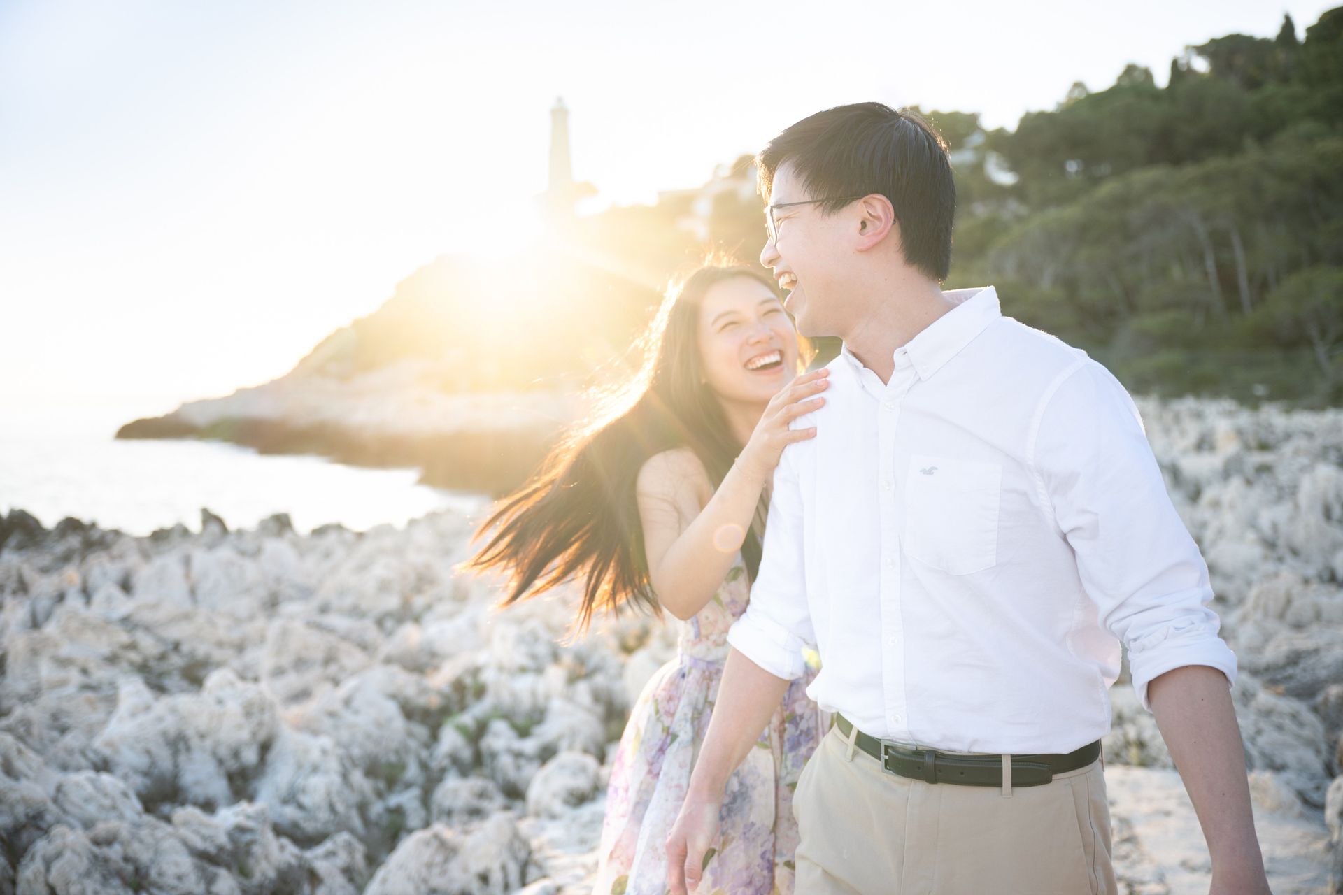 A couple laughing and smiling near a lighthouse at sunset in the south of France.