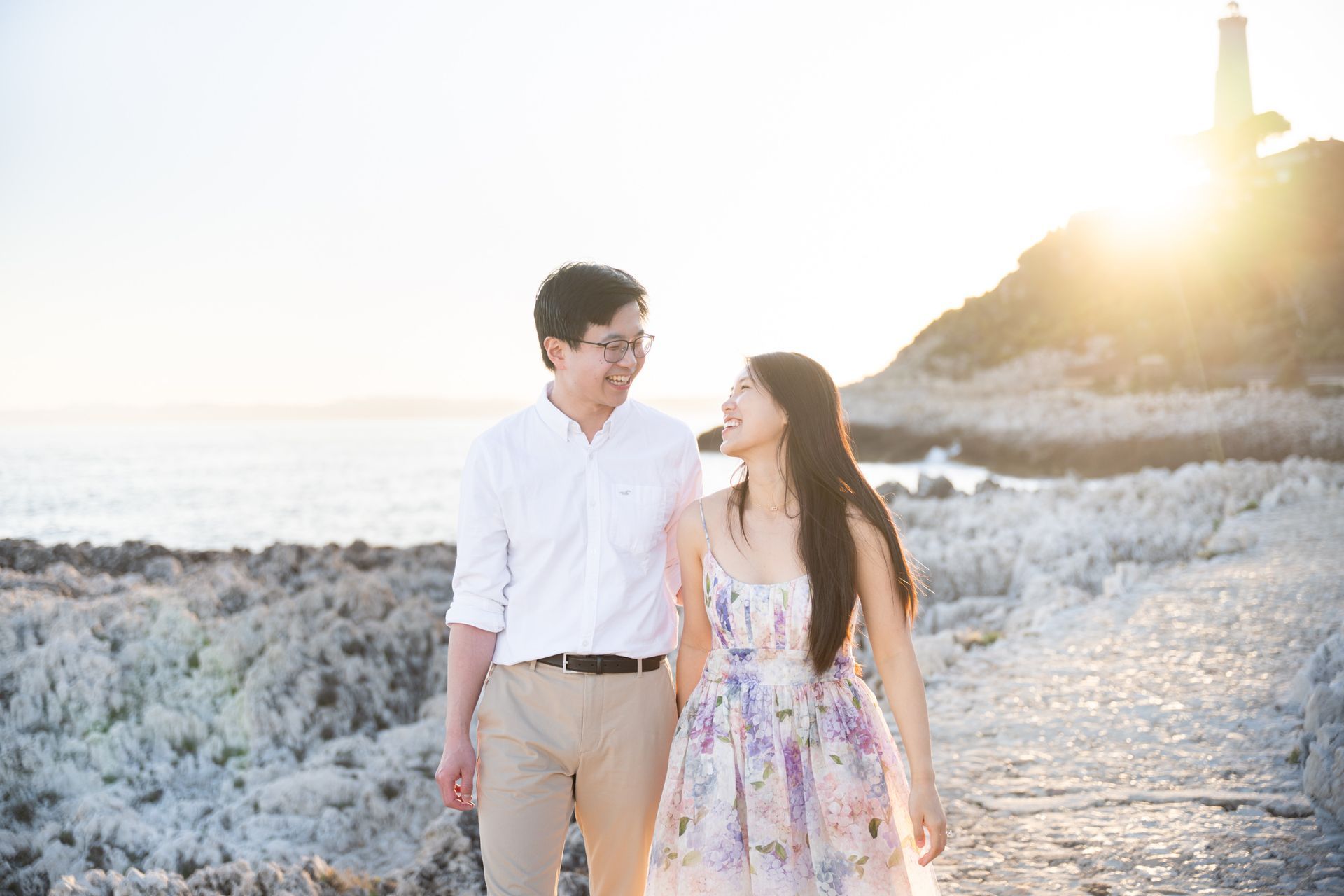 A couple laughing and smiling near a lighthouse at sunset in the south of France.