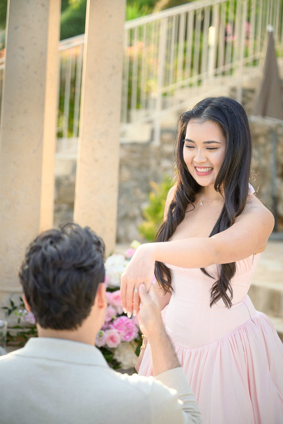 A woman smiles while a man gets on one knee in Eze, South of France, and proposes.
