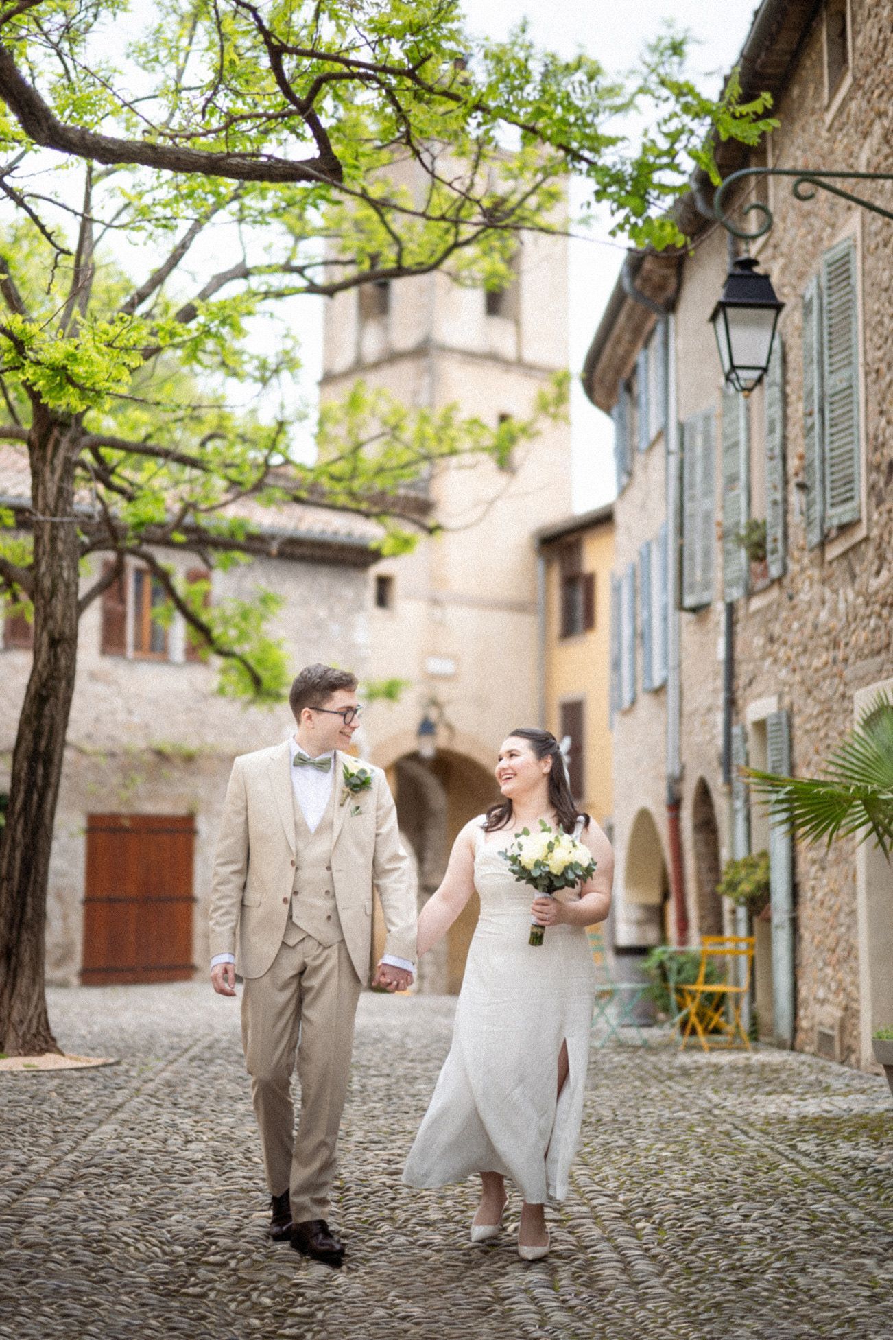 Natural and candid image of bride and groom interacting as they walk through the streets of Cagnes Sur Mer, Provence, on their wedding day.