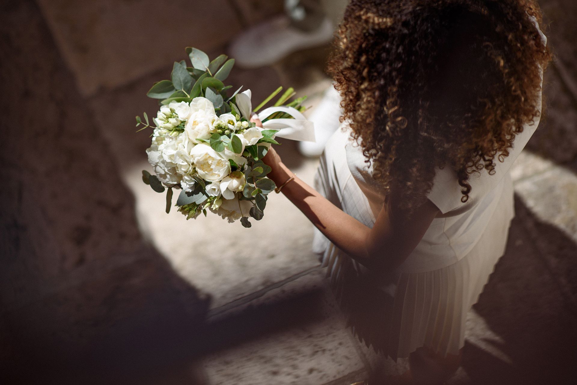 Bouquet de mariée composé de fleurs blanches et crème, avec un éclairage artistique et spectaculaire.