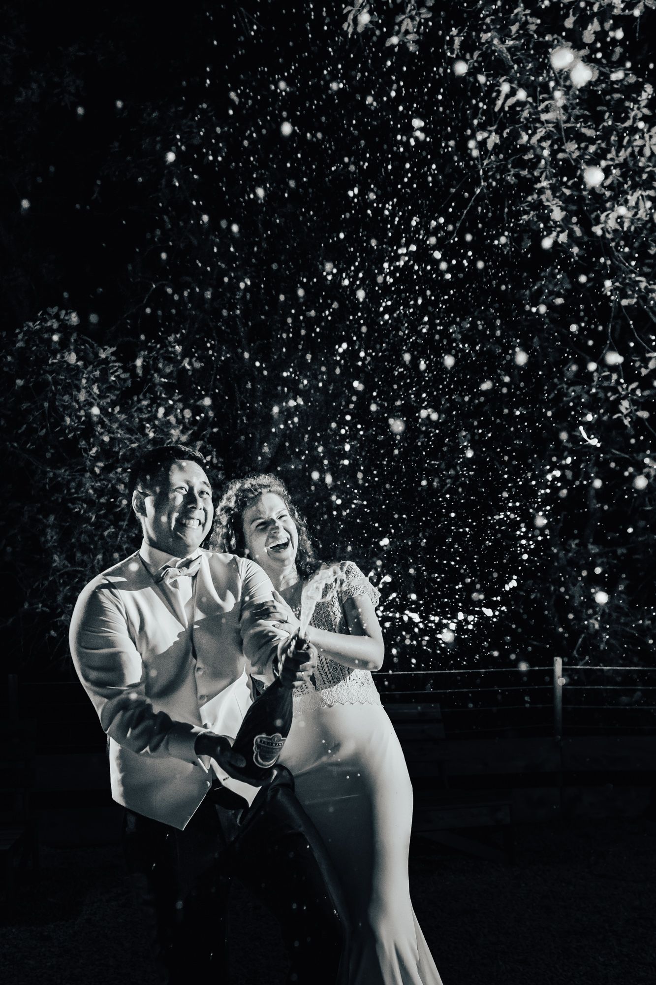A couple open champagne at night time at a luxury wedding in Provence