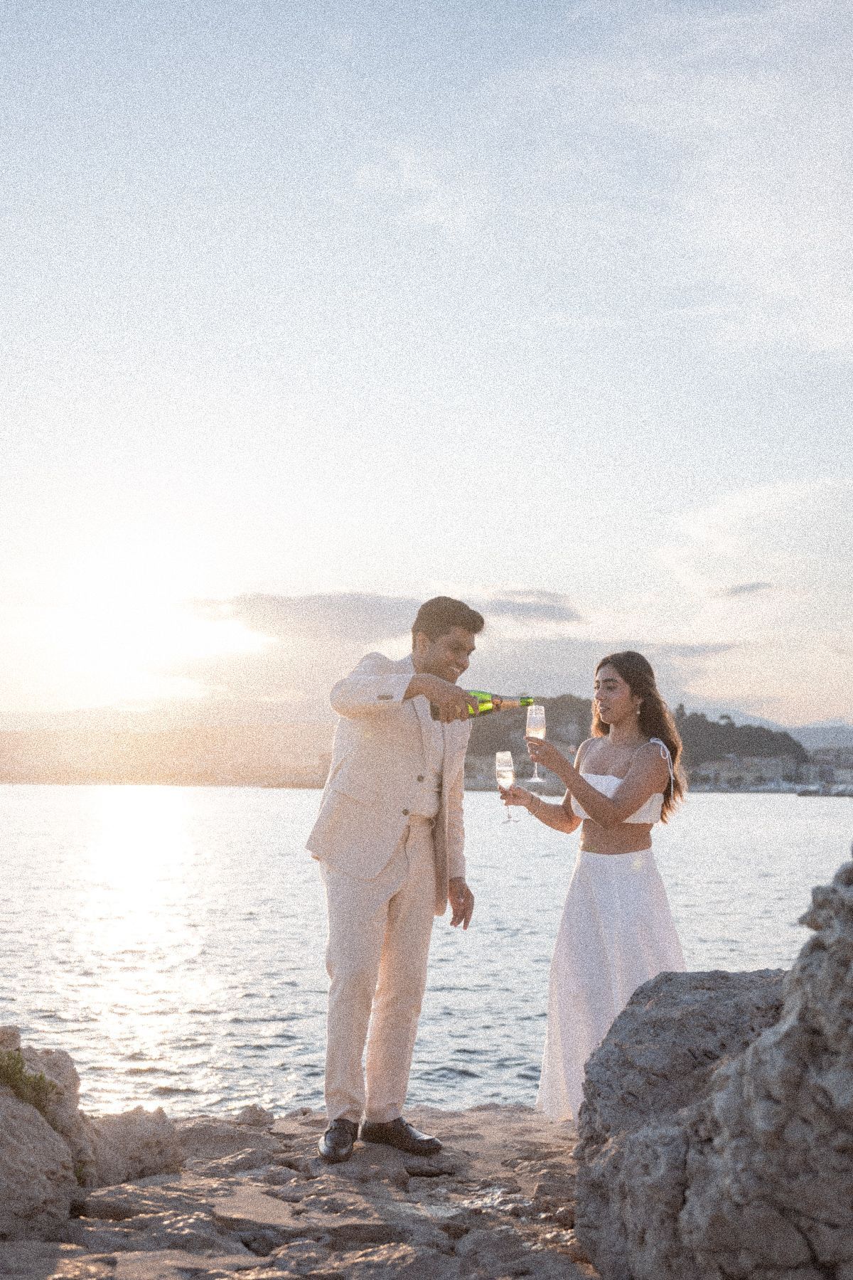 A couple pour champagne during an engagement photoshoot in Nice, France.