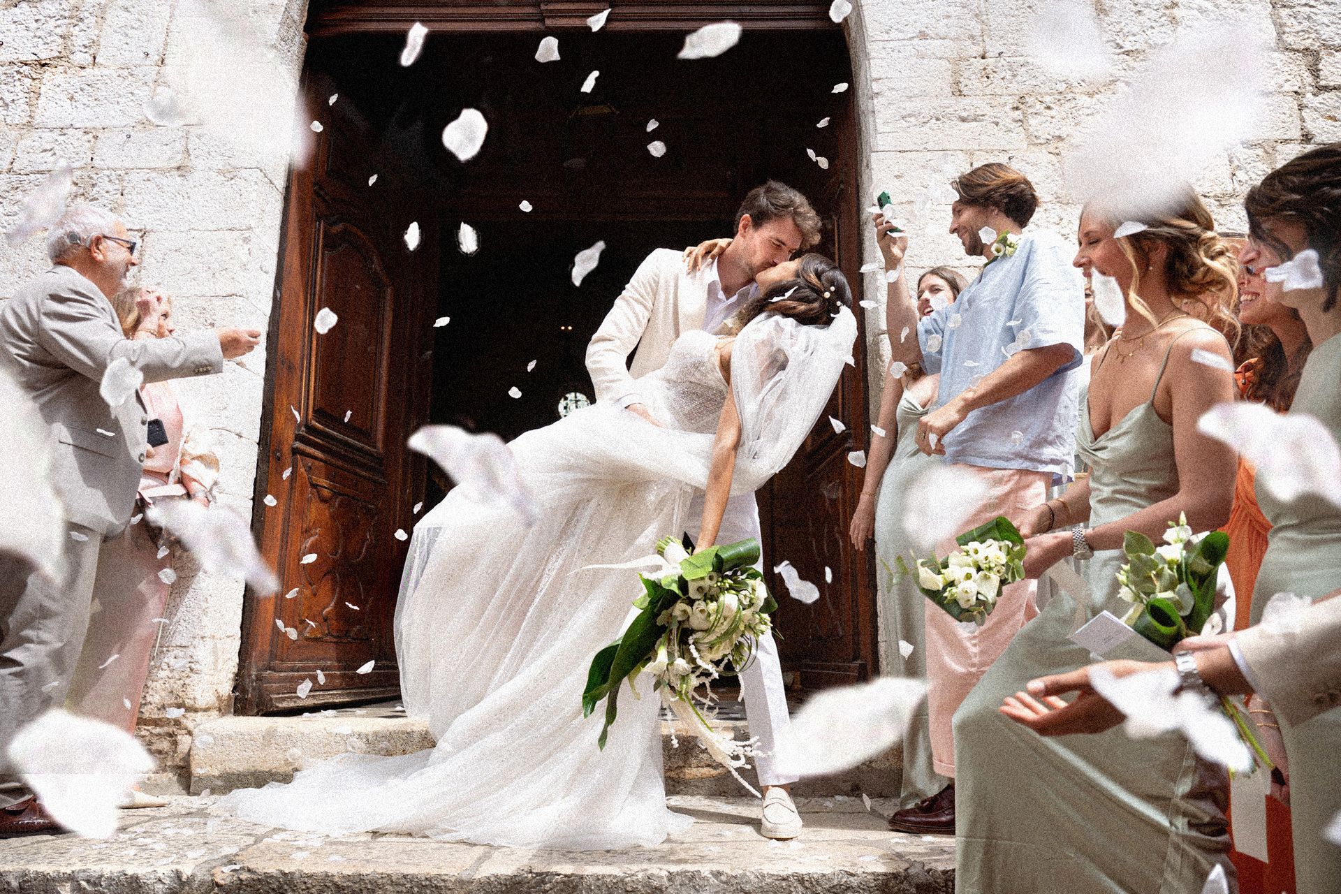 Un mariage à Saint Paul de Vence, les jeunes mariés s'embrassent sous une pluie de confettis
