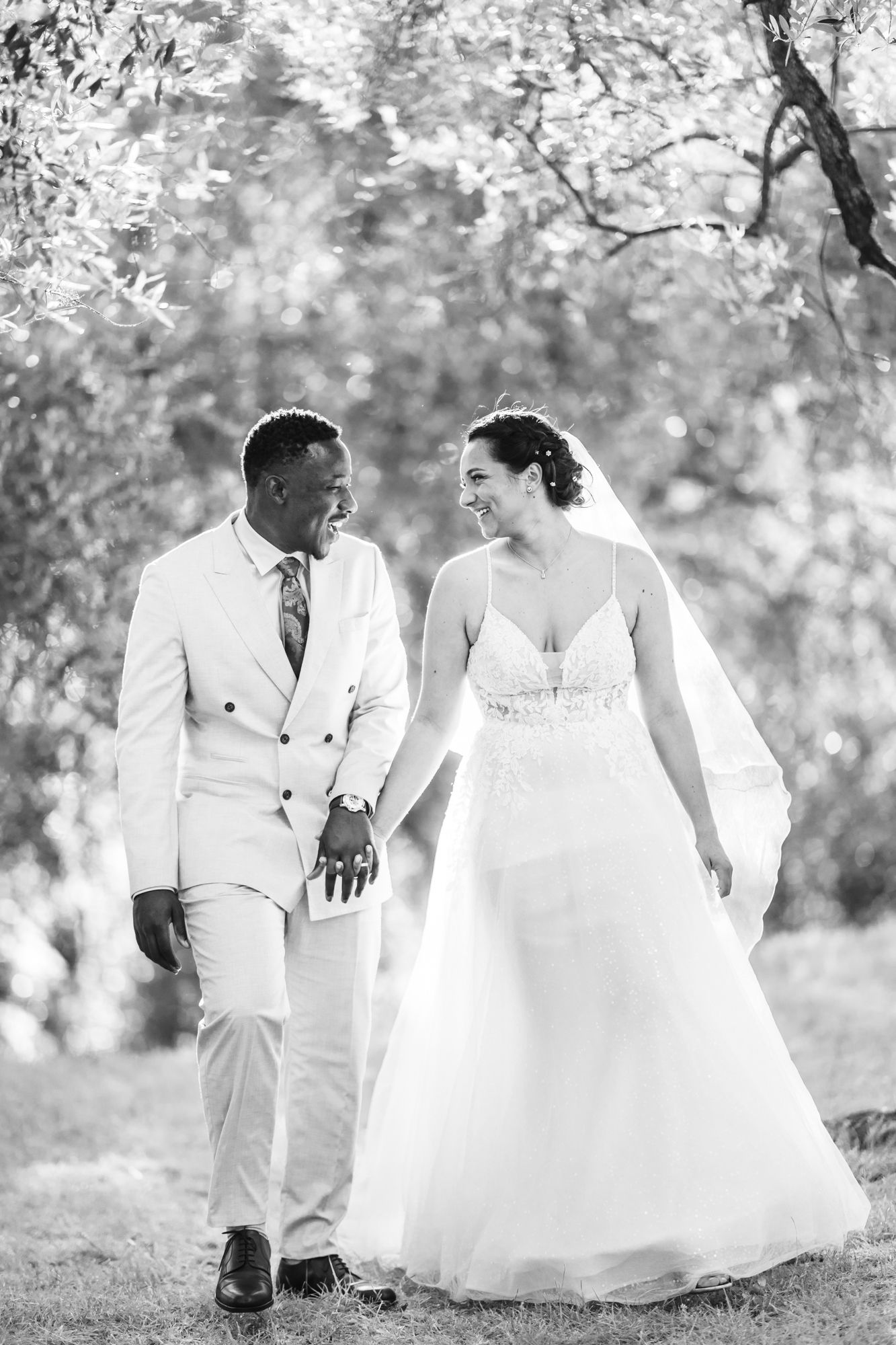 une séance de photos de mariage détendue, naturelle et amusante dans une oliveraie. Le couple marche et rit