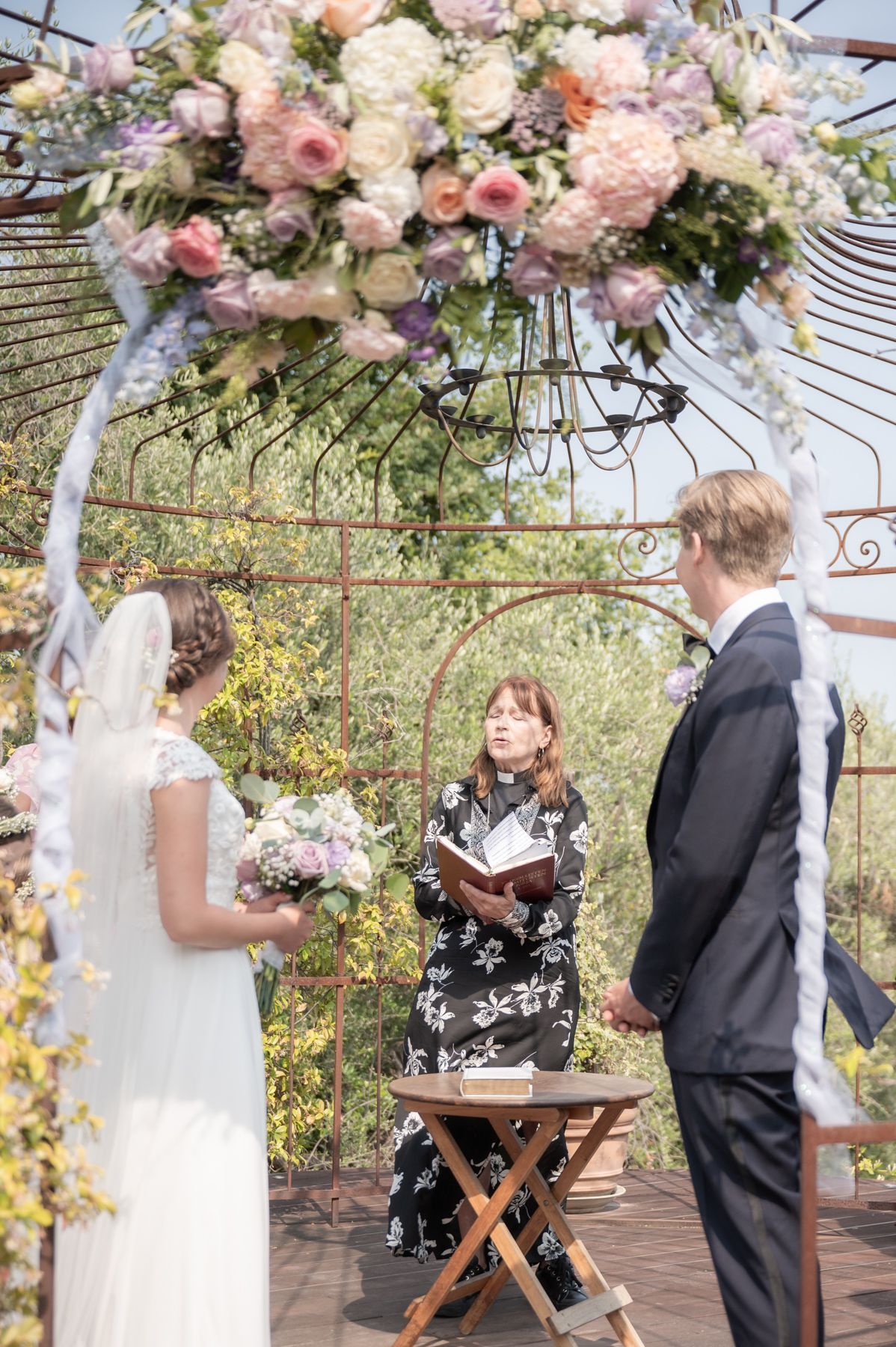 une cérémonie de mariage à la campagne sous une véranda décorée de fleurs et de rubans
