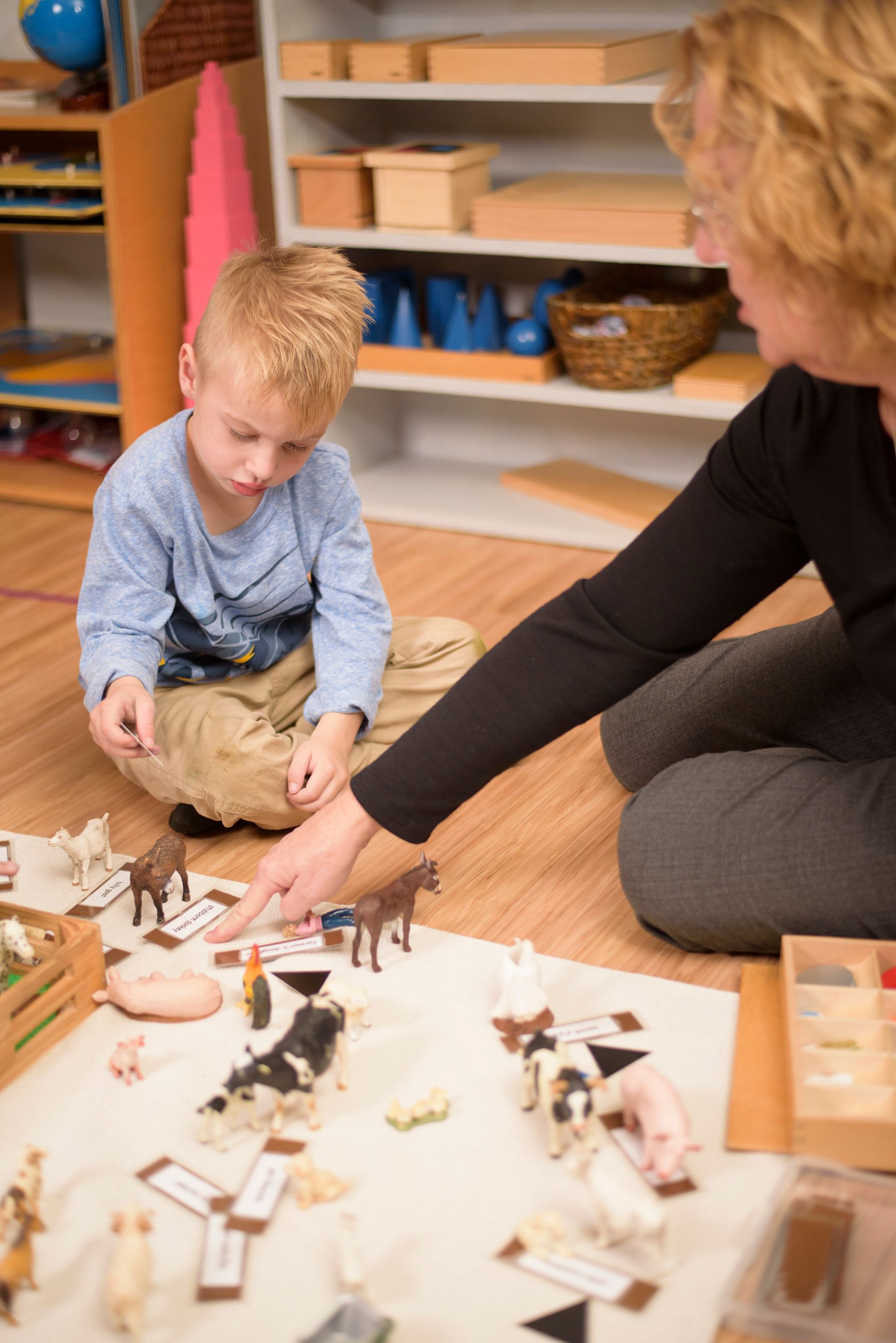 Adult and child working with the barn on the floor in a classroom