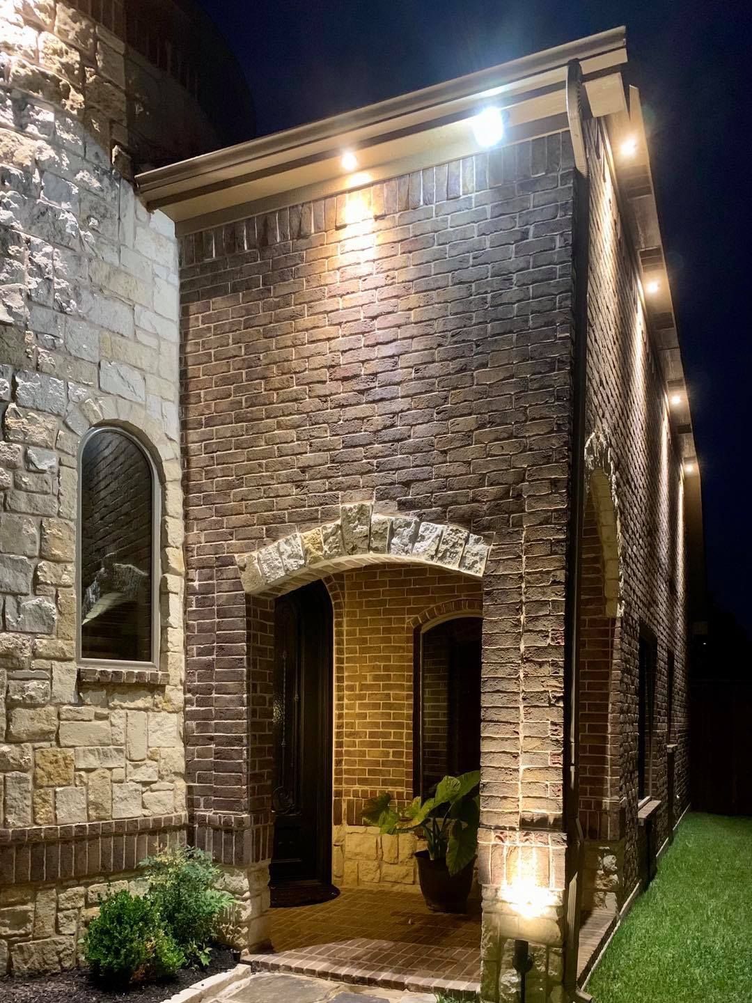 Lit brick building with arched entryway and warm exterior lights at night