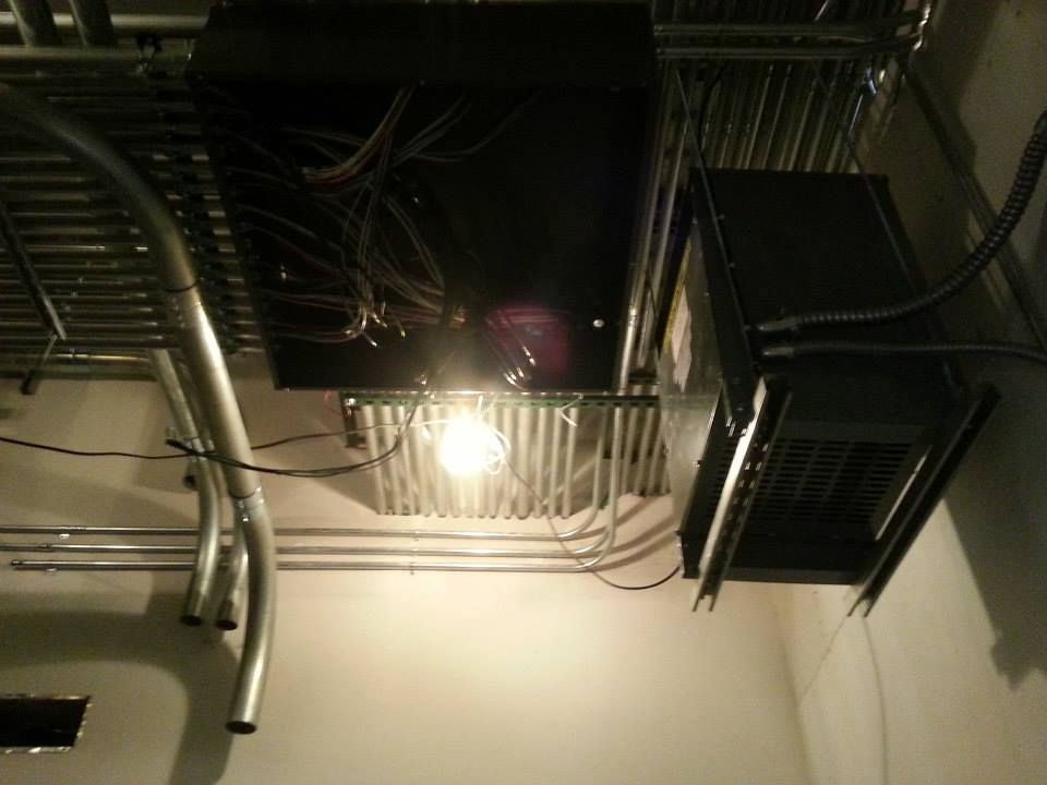 Ceiling with exposed pipes, wiring, and vents above a bright light in an industrial interior