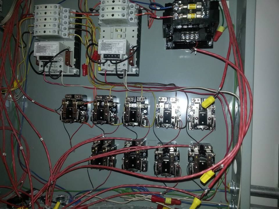 Electrical control panel with relays, wiring, and circuit modules mounted inside a metal enclosure