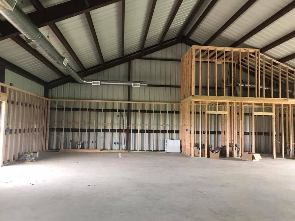 Empty warehouse with exposed metal framing and a partially built wooden loft on the right