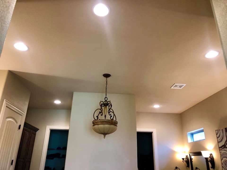 Ceiling-lit hallway with beige walls, hanging chandelier, and open doorways.