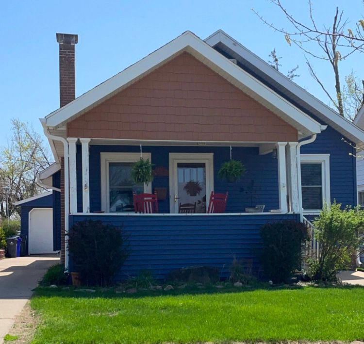 A blue house with a porch and a chimney