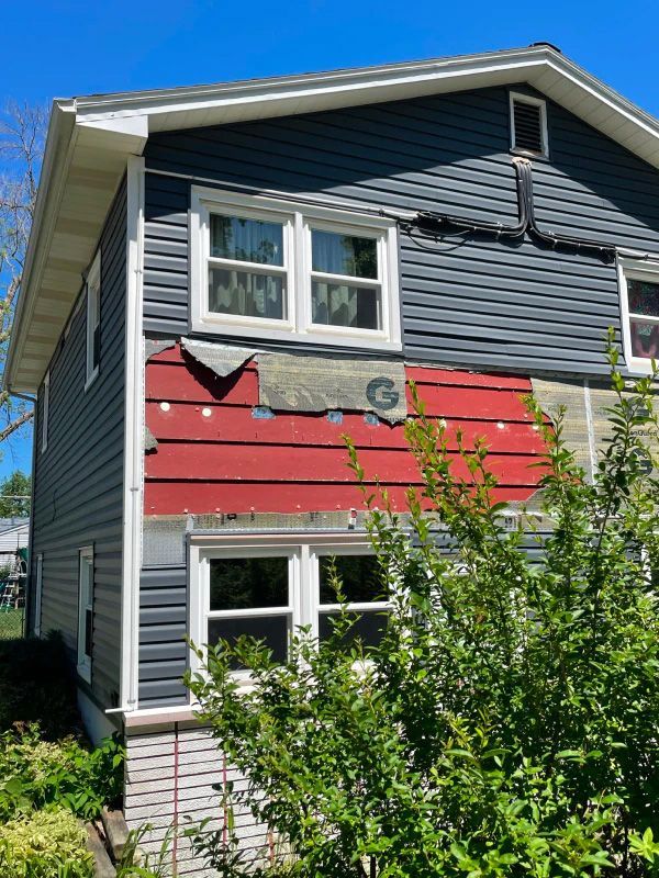 A house with a red siding is being remodeled.
