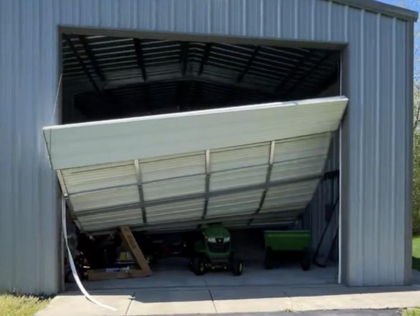 Collapsed garage door bent inward, blocking a shed entrance with equipment visible inside.