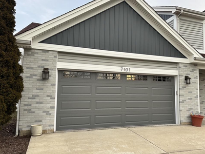 Suburban house front with gray garage door, stone siding, and concrete driveway
