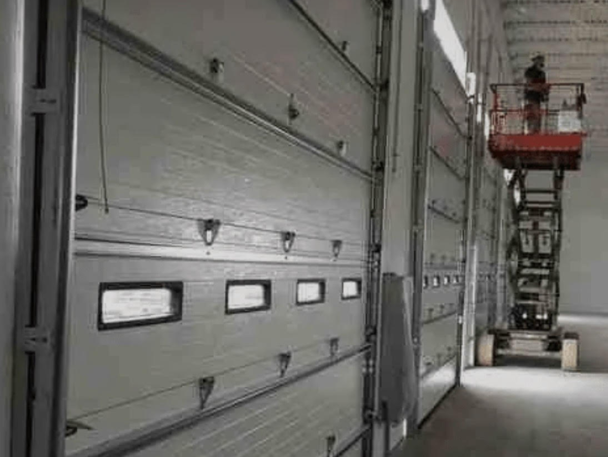Industrial warehouse loading dock with large gray bay doors and a lift platform on the right