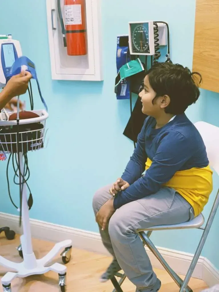 A young boy is sitting in a chair while a doctor examines him