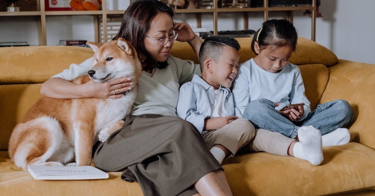 A woman is sitting on a couch with two children and a dog.