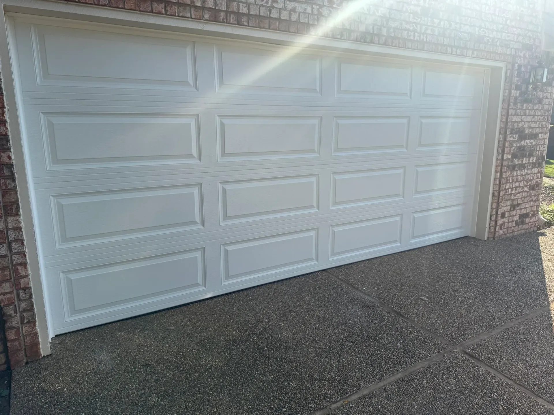 White panel garage door, closed, in a brick building.