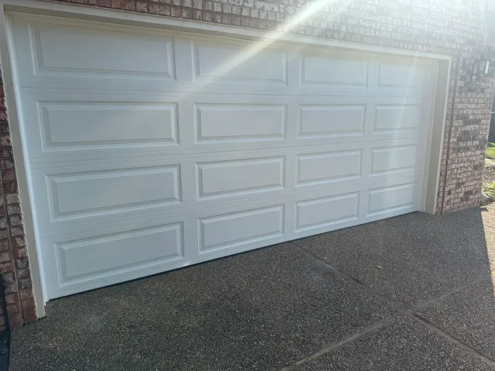 White panel garage door, closed, in a brick building.