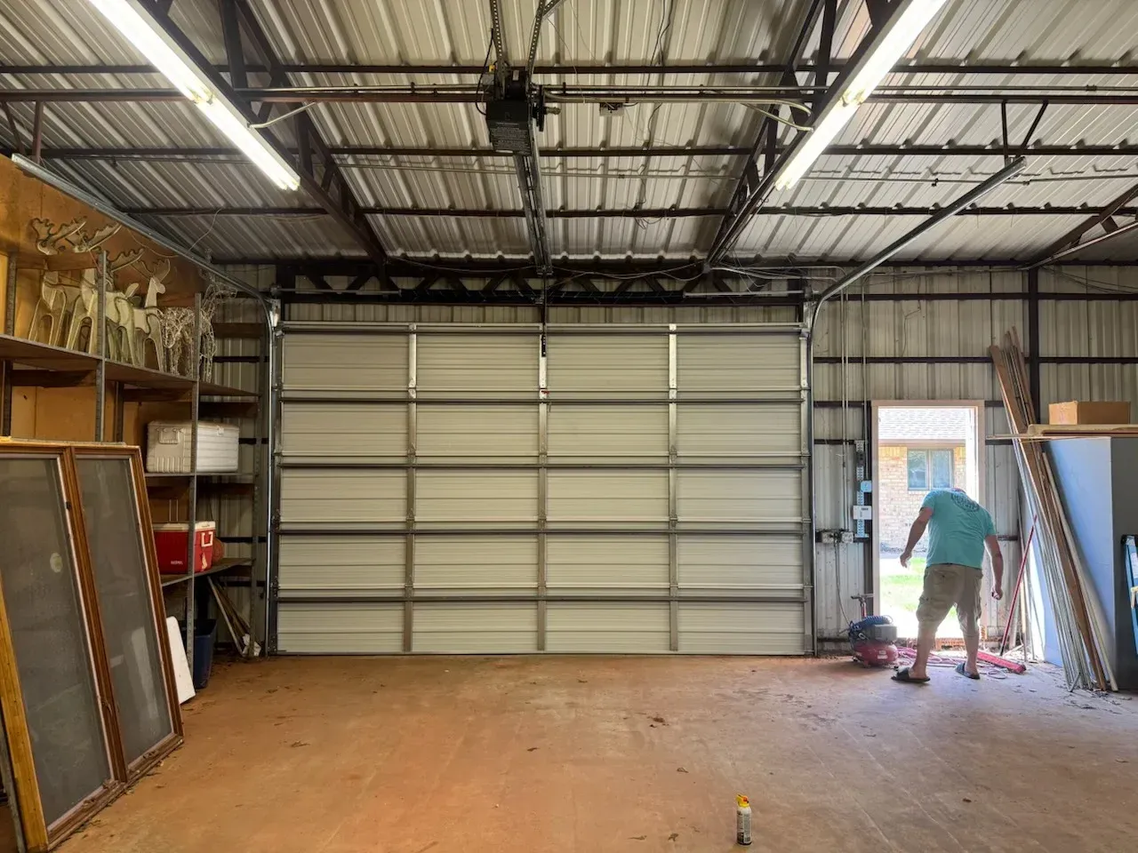 Garage interior with closed white door, person standing near open doorway.