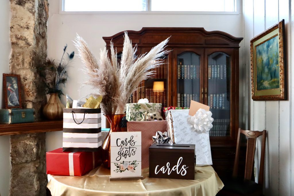 Gift table with wrapped presents, cards, and pampas grass in a cozy dining room