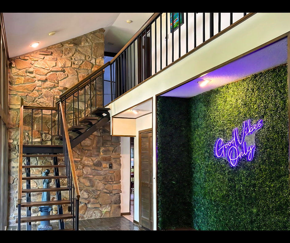 Stone staircase beside a green wall with purple neon sign in a modern interior