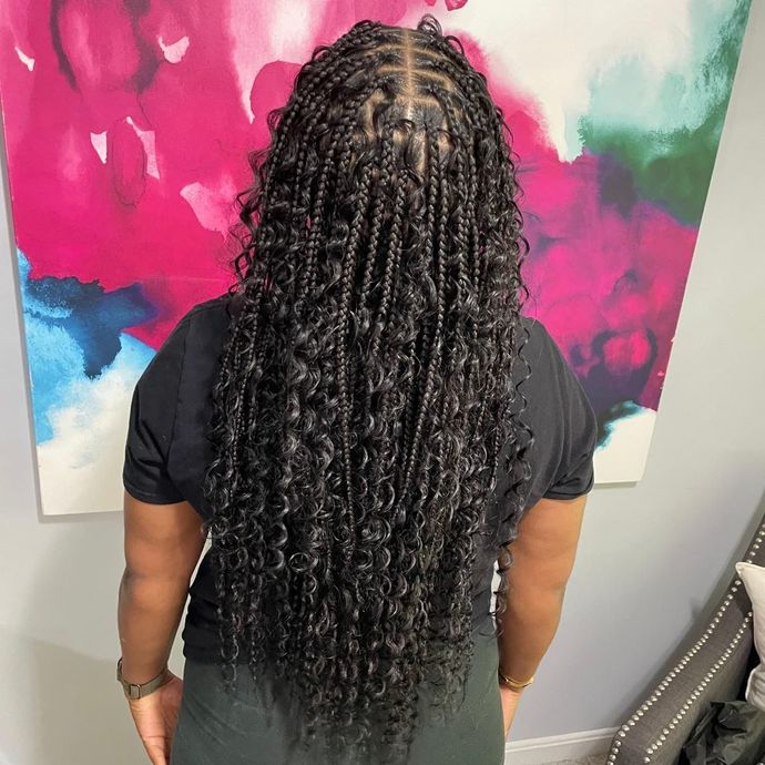 Person with long braided hair standing before a colorful abstract painting