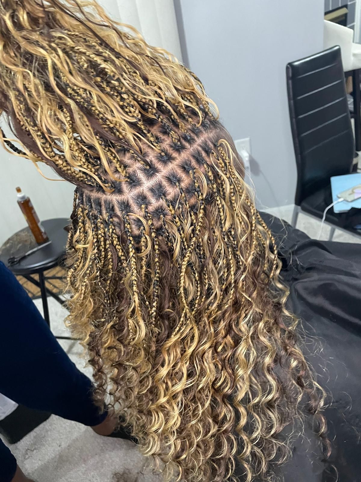 Close-up of long blonde braided hair with a neat parted scalp pattern in a salon chair
