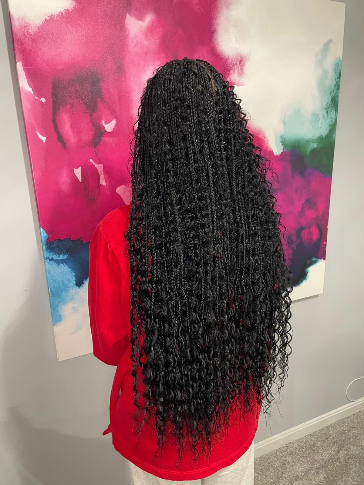 Person in a red top with long curly black hair standing before a pink, blue, and white abstract painting